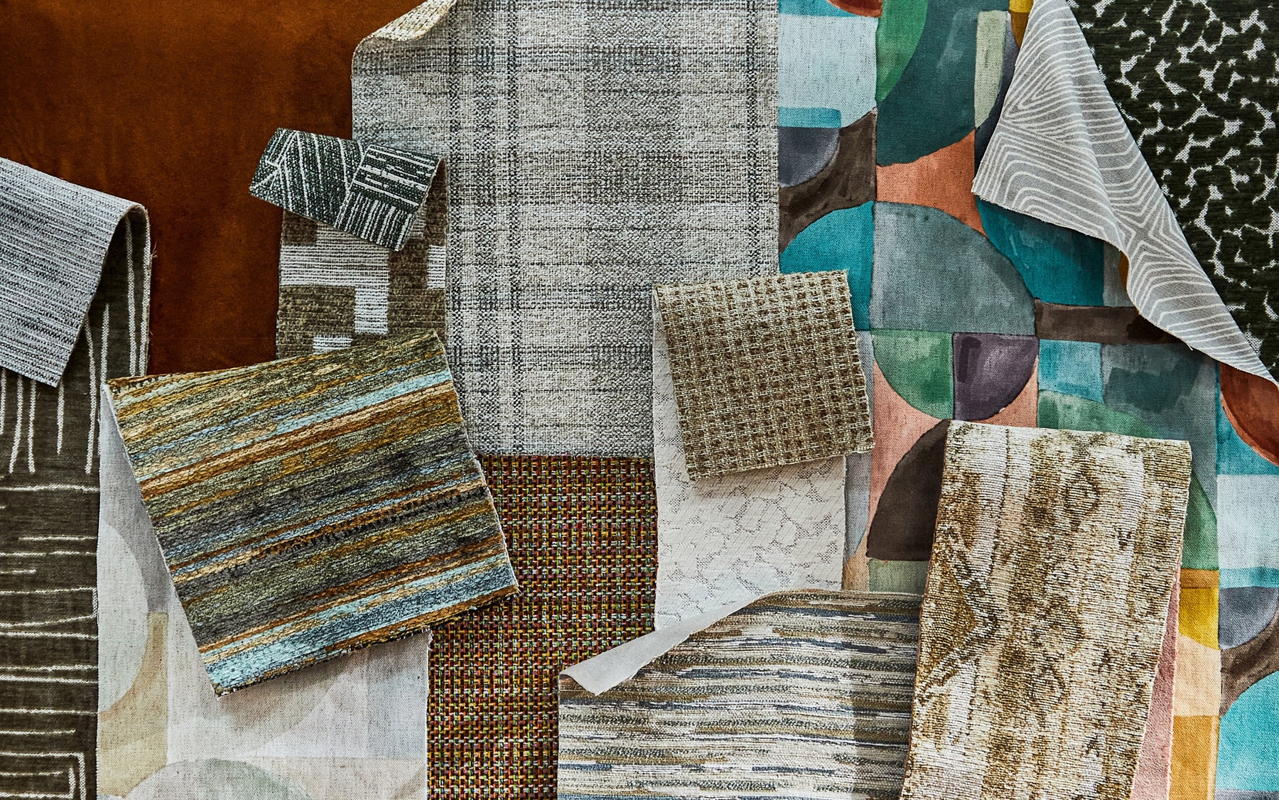 Assorted Revolution Performance Fabric samples in various colors, patterns, and textures, displayed in an overlapping arrangement. The samples include stripes, geometric designs, and textured weaves, showcasing the diversity of upholstery fabric options.