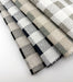 Fanned swatches of Revolution Performance Fabric, pattern Brompton in Indigo, Black, Taupe, and Spa, showcasing classic buffalo check upholstery fabric in versatile neutral and blue-green colorways.