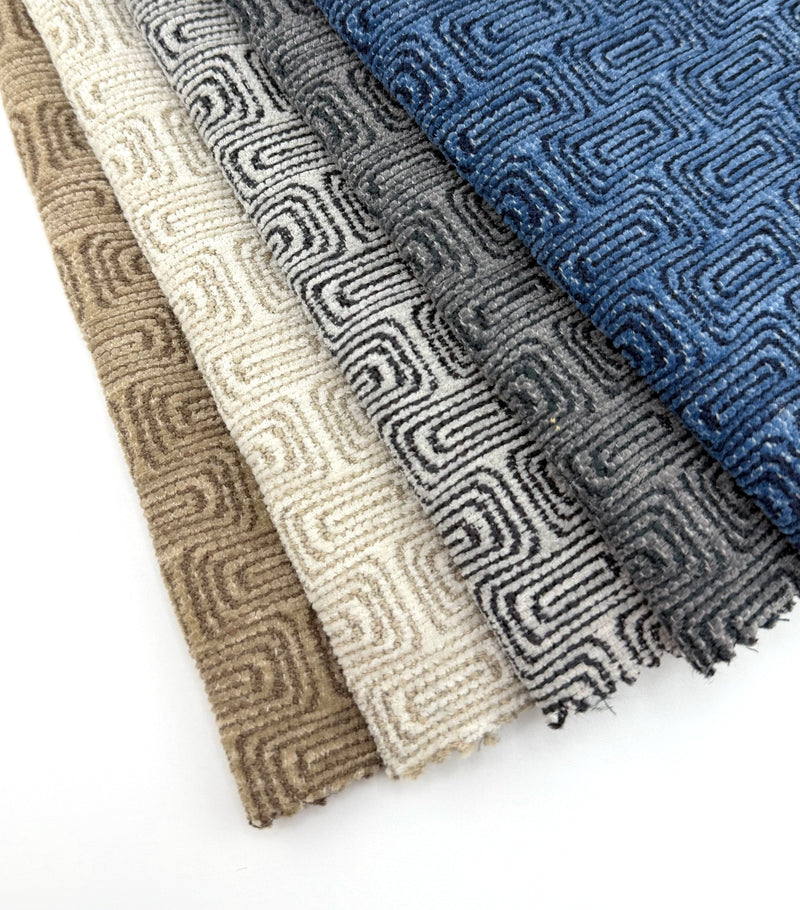 Assorted Revolution Performance Upholstery Fabric swatches from the Collide collection arranged in a fanned layout. Each swatch displays Collide’s raised geometric pattern with interlocking linear motifs and a plush, dimensional texture with subtle tonal variation.