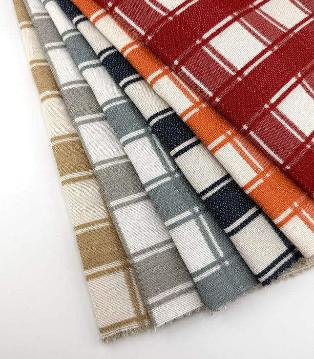 Fanned view of Revolution Performance Upholstery Fabric in the Denmark collection, showcasing a classic plaid pattern across all colorways. Each swatch displays Denmark’s layered vertical and horizontal bands, creating a timeless, tailored look. The tightly woven texture highlights the crisp structure of the design.