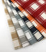 Fanned view of Revolution Performance Upholstery Fabric in the Denmark collection, showcasing a classic plaid pattern across all colorways. Each swatch displays Denmark’s layered vertical and horizontal bands, creating a timeless, tailored look. The tightly woven texture highlights the crisp structure of the design.