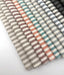 Assorted Revolution Performance Upholstery Fabric swatches from the Foreshore collection arranged in a fanned layout, showing multiple colorways including sand, walnut, conch, mint, bottle, mango, red, marine, onyx, and carbon. Each swatch displays Foreshore’s evenly spaced vertical stripe pattern with subtle tonal variation.