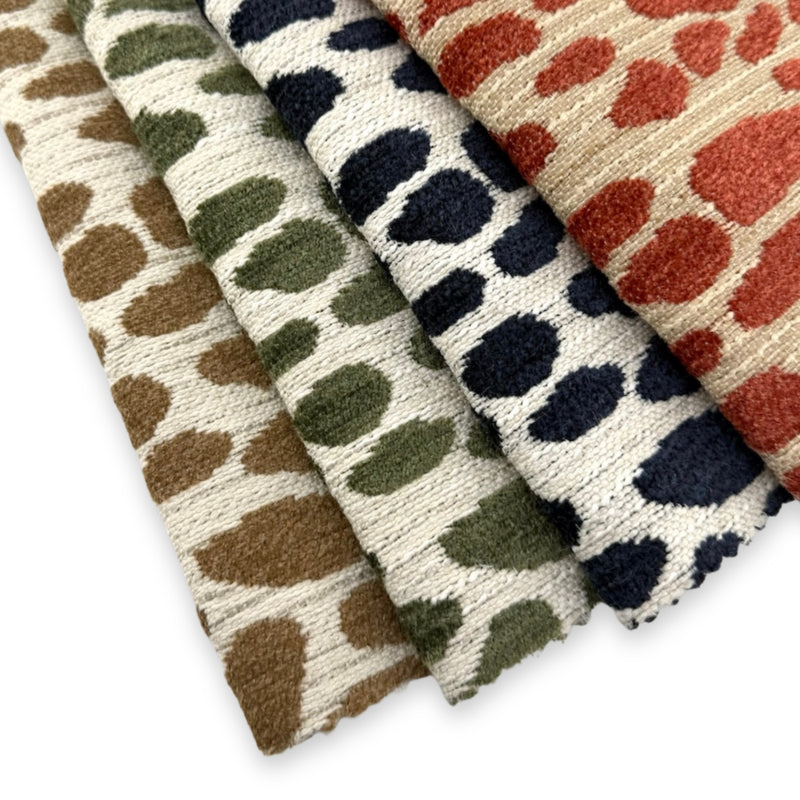 Revolution Performance Fabric swatches arranged in a fanned layout, featuring the Winging It pattern in multiple colorways including jute brown, thyme green, navy blue, and persimmon orange, woven with an abstract scattered motif across an ivory textured ground in a durable, high-performance upholstery fabric suitable for indoor and outdoor use.