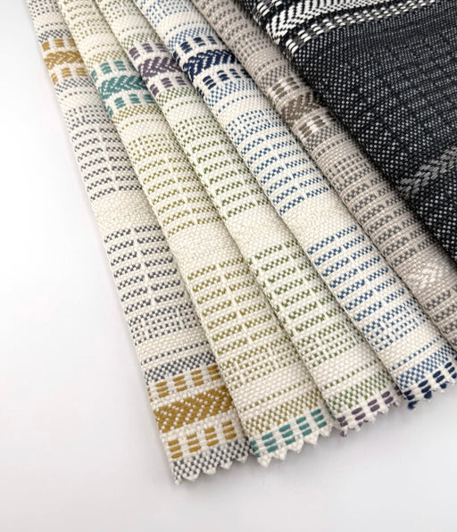Revolution Performance Fabric Lloyd collection swatches arranged in a fanned layout, showcasing multicolor vertical stripe patterns in ivory, sage green, navy, taupe, gold, and charcoal with a textured woven upholstery finish.