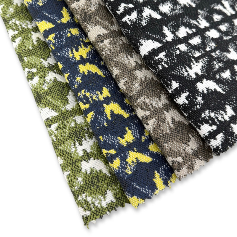 Assorted Revolution Performance Fabric swatches in the Polynesian pattern arranged in a fanned layout, showcasing green, navy with yellow accents, warm taupe, and black-and-ivory colorways. Each fabric features abstract geometric motifs woven with a textured finish, highlighting the durability and visual depth of the upholstery collection.
