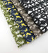 Assorted Revolution Performance Fabric swatches in the Polynesian pattern arranged in a fanned layout, showcasing green, navy with yellow accents, warm taupe, and black-and-ivory colorways. Each fabric features abstract geometric motifs woven with a textured finish, highlighting the durability and visual depth of the upholstery collection.

