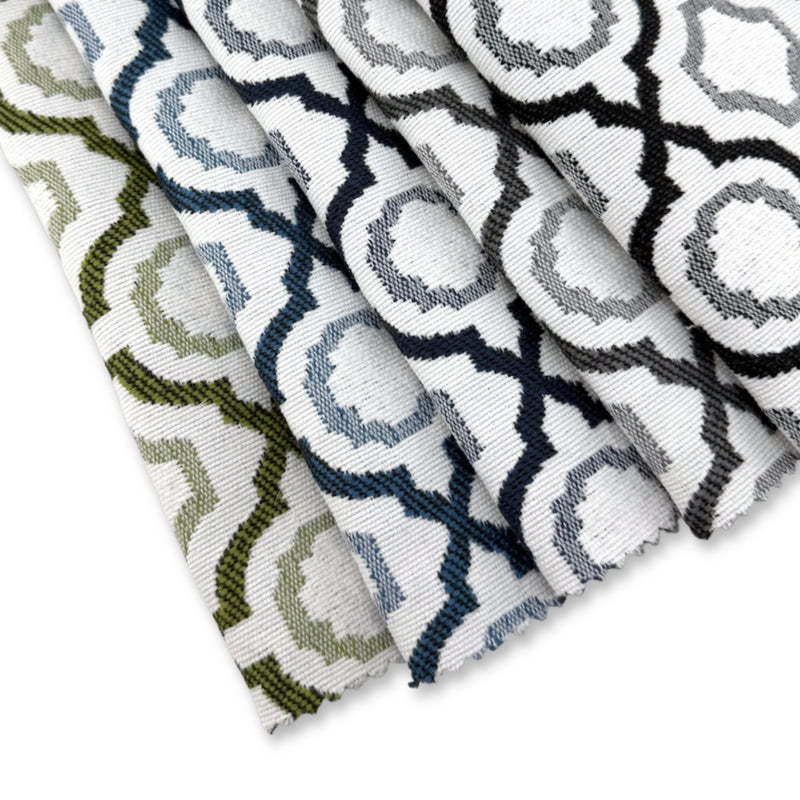 Assorted Revolution Performance Fabric swatches in the Savannah pattern arranged in a fanned layout, showcasing green, navy, blue, grey, and black geometric lattice designs woven over an ivory base for durable, high-performance upholstery applications.