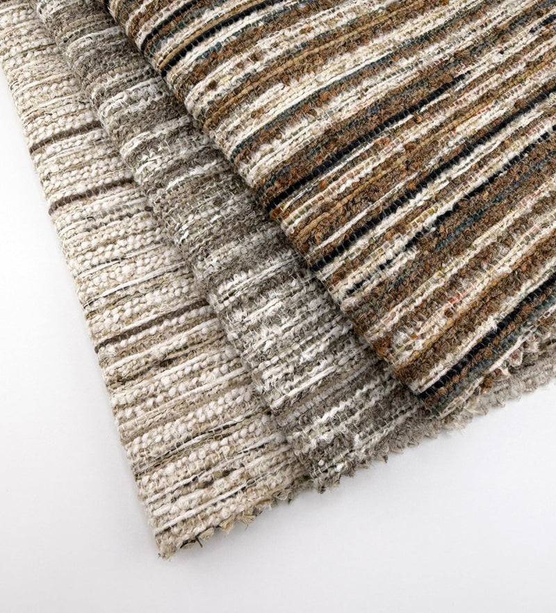 Assorted Revolution Performance Upholstery Fabric swatches from the Variegate collection arranged in a fanned layout. Each swatch displays Variegate’s narrow vertical striping with a softly ribbed woven texture, subtle yarn variation, and layered tonal depth across neutral colorways.