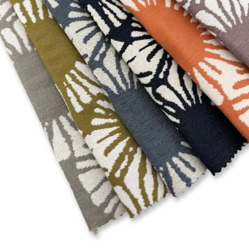 Revolution Performance Fabric Sunburst pattern swatches arranged in a fanned layout, showcasing multiple colorways including citron, indigo, mango, lapis, loft, and passion, each featuring bold radiating sunburst motifs on an ivory ground with a textured, high-performance upholstery weave.