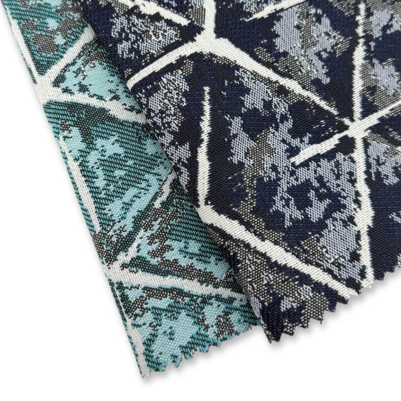 Revolution Performance Fabric swatches featuring the Sarong pattern in Navy and Teal colorways, stacked to showcase geometric cube motifs with layered tonal texture and ivory linework for modern, durable upholstery applications.
